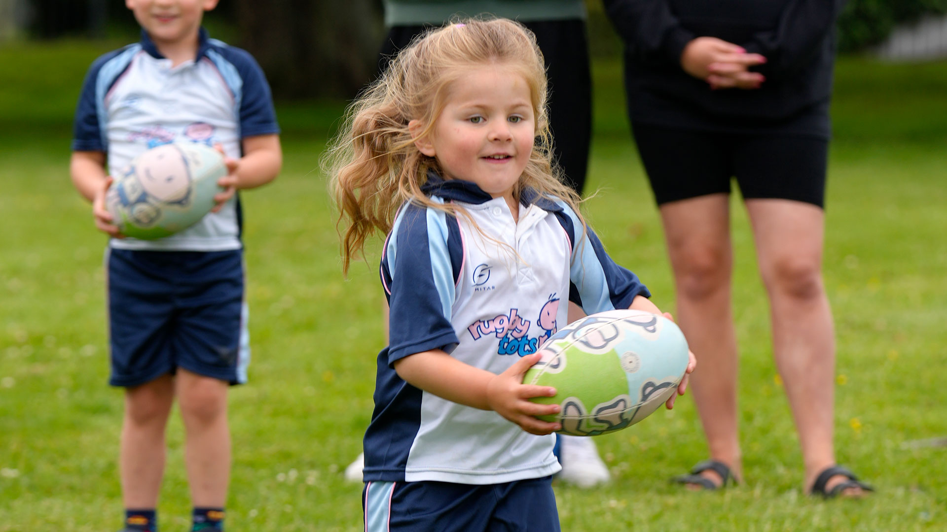 Girl confidently running with a rugby ball.