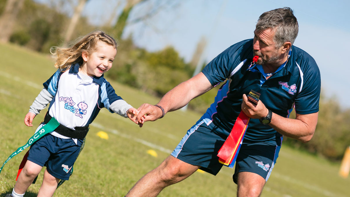 Girl getting some helpful encouragement from her Rugbytots coach.