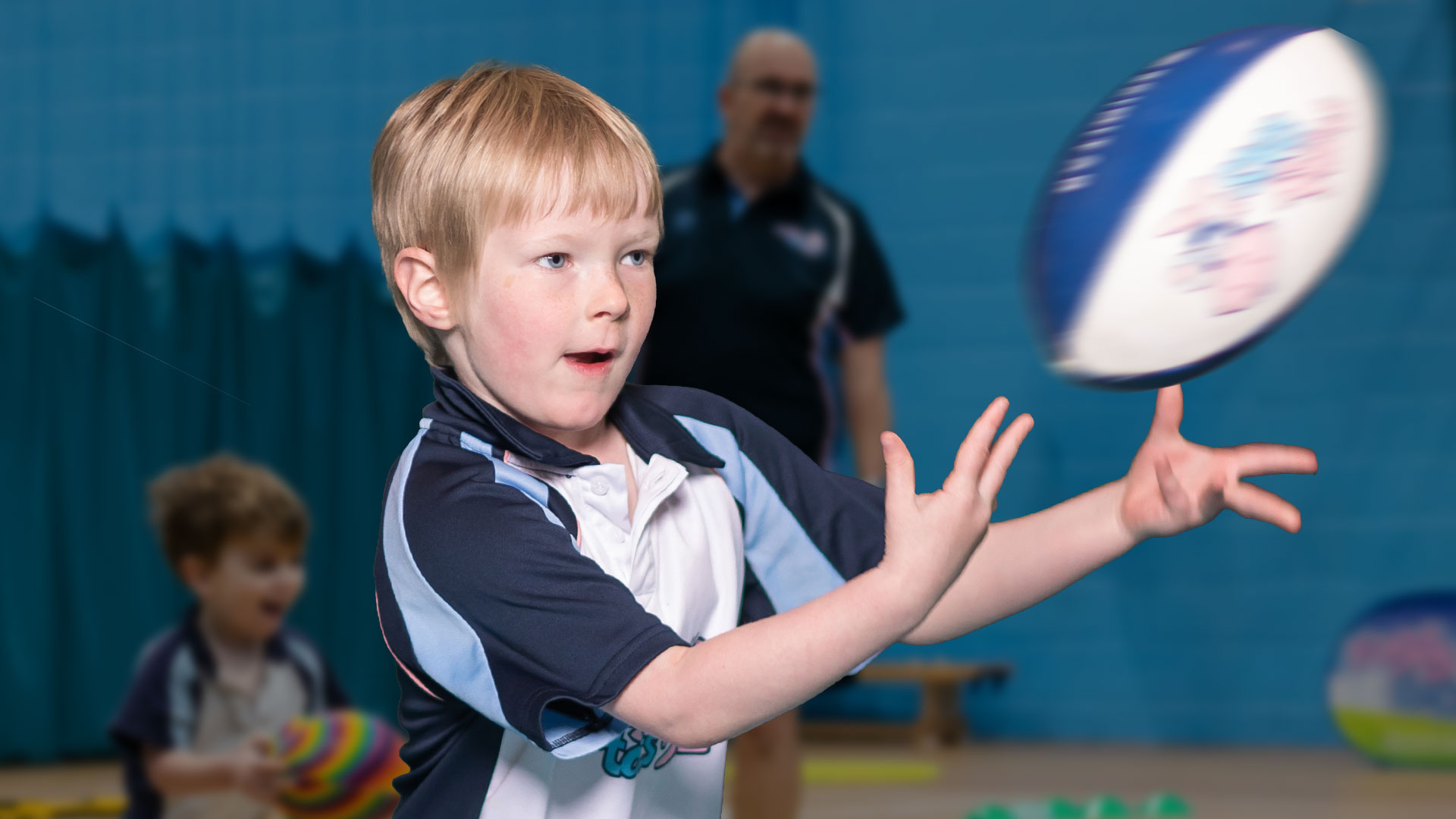 Boy passing a rugby ball in a Rugbytots class.